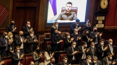 Getty Images ROME, ITALY - MARCH 22: Ukrainian President Volodymyr Zelensky addresses the Italian Parliament via live video from the embattled city of Kyiv on March 22, 2022 in Rome, Italy.