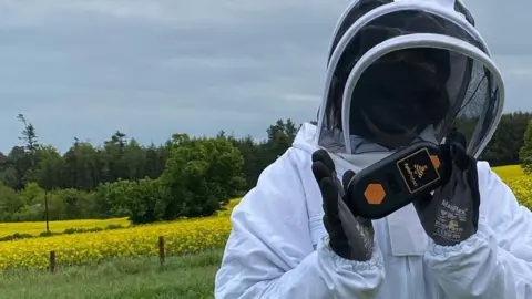 ApisProtect A beekeeper holding an ApisProtect monitor