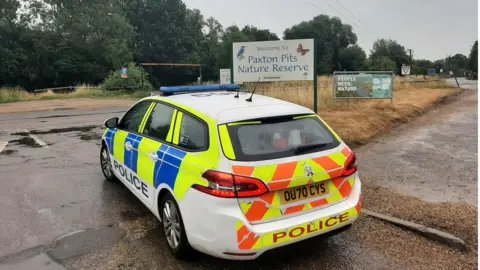 Cambridgeshire Constabulary Police car in front of a Paxton Pits sign