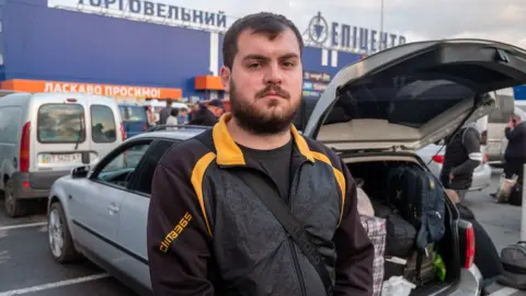 BBC Anton Osenev standing next to a car boot that contains luggage