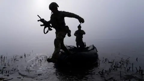 AP A Ukrainian serviceman jumps out of a boat on the shore of the Dnipro river at the frontline near Kherson, Ukraine, Sunday Oct. 15, 2023.