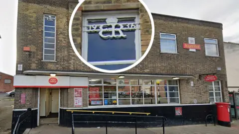The Post Office branch on Chester-le-Street's Front Street. The building is in Art Deco-style made of brown brick and has a modern Post Office signage outside in red and white. The cypher, which is white, is on a window. It has a crown above it and reads 19 ER 36 with the Roman numerals VIII under it. It has also been put into a separate circle in the picture to show it more clearly.