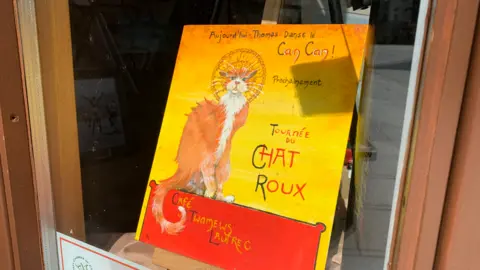 The famous Le Chat Roux work in yellow and red features the ginger cat and Thomas's name.
