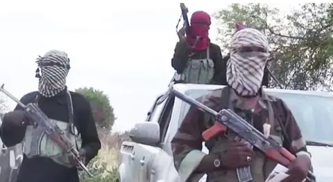 Boko Haram Three members of Boko Haram, pictured here in a propaganda video, wear traditional cloths wrapped around their heads concealing their mouth and nose, holding guns. 