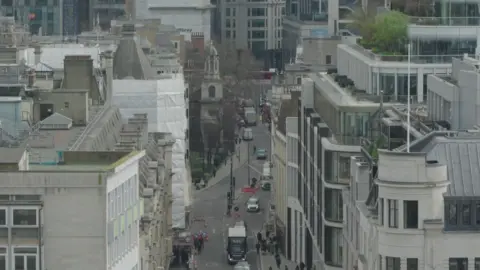 A skyline of highrise buildings with traffic and people seen below.