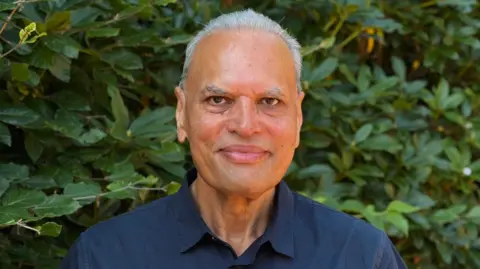Gurd Chahal stood against a backdrop of trees and bushes, wearing a blue shirt
