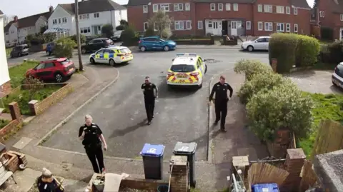Supplied A group of police officers stand in front of a house