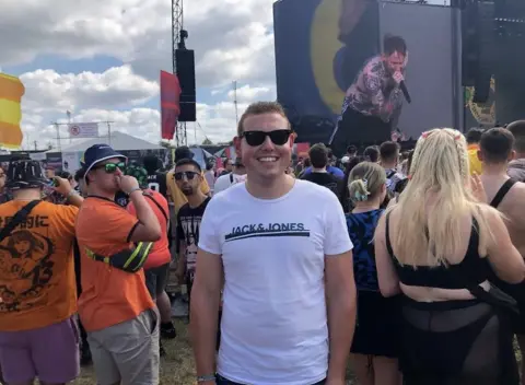 Alex Richardson A man in a white T-shirt smiles in a festival crowd.