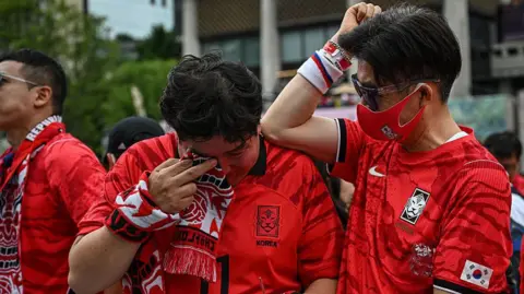 Getty Images South Korean fans react after their team lost the 2026 World Cup football match against South Africa at Gwanghwamun Square in Seoul on June 25, 2026. 