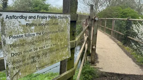 A view of signage near the footbridge outlining byelaws about things such as keeping to the paths and keeping dogs on leads