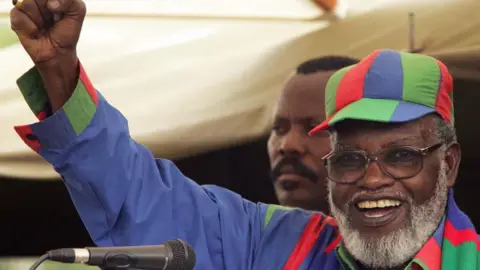 AFP Namibian President Sam Nujoma, wearing a red, green and blue shirt with matching cap, addresses a rally in Windhoek to support his hand-picked successor candidate, Hifikepunye Pohamba, 13 November 2004.