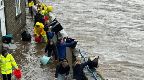 Residents try to bail water away from their homes in Pontypridd, south Wales