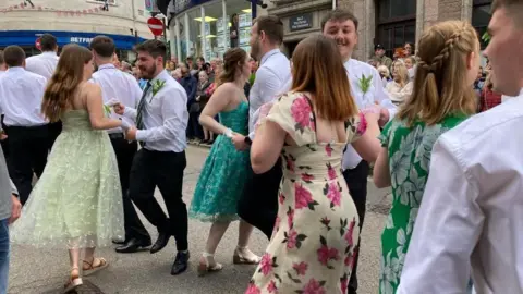 BBC women in dresses and men in smart trousers and white shirts dancng
