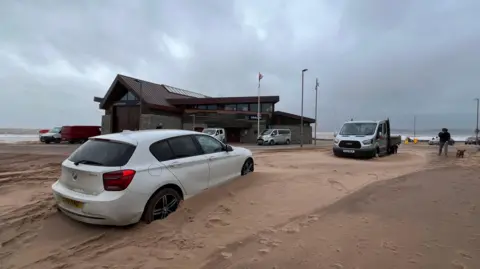 A car and a truck stuck in sand drifts