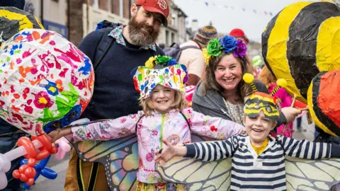 Paul Campbell A family dressed in colourful clothes and paper masks and butterfly wings.