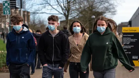 Four students wearing face masks walk through the University of Kent in Canterbury campus after an outbreak of meningitis caused the deaths of two people in March 2026. 
