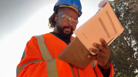 Emmanuel looking at a notepad and writing on it.