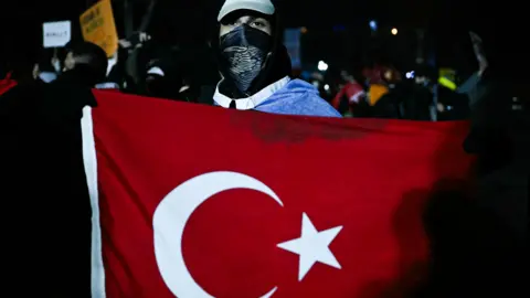 A protester holds a Turkish flag while wearing a face covering during a demonstration in Istanbul