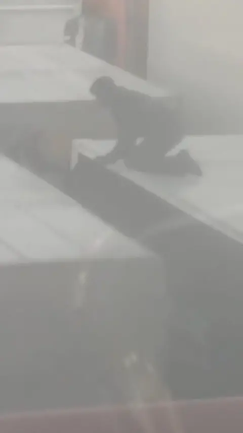 Man on top of lorry with other lorries surrounding it in foggy conditions