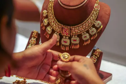 Getty Images A woman looks at a gold necklace and earrings at a jewelry store in Zaveri Bazaar on Tuesday during the Dhanteras festival in Mumbai