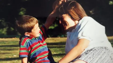 LIAM KIPPAX A photograph of Liam as a child playing with his mum's hair, who's smiling back at him.