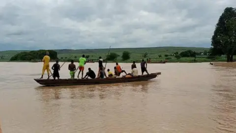 People travel by a boat as search and rescue operations continue following a boat accident, in a place given as Sokoto State, Nigeria. 