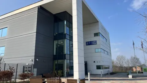 The outside of Cleveland Police station. It is a large white and grey panelled building with glass doors. 