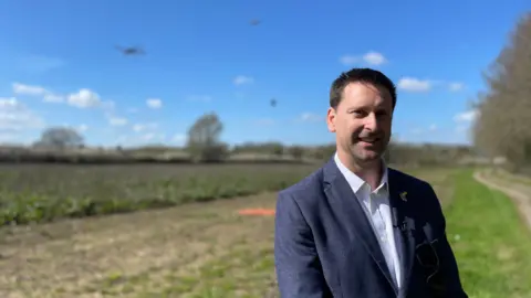 A man in a suit with drones flying around him