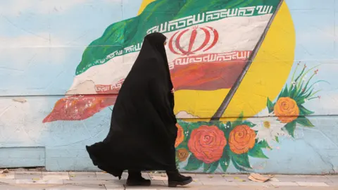 A woman walks after the morality police shutdown in a street in Tehran, Iran