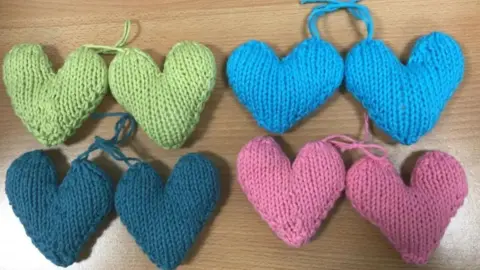 Four pairs of knitted hearts, one pair is light green, one light blue, one dark blue and the other is pink