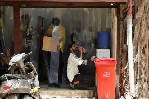 Reuters Delivery partner with Blinkit, an Indian online-delivery company, drinks water outside one of the company's dark stores