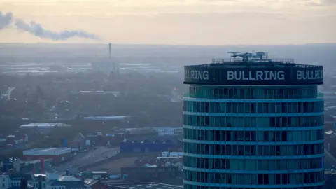 The Birmingham skyline with the Rotunda in the foreground and a smoking chimney in the background