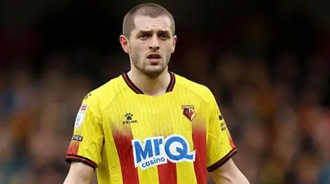 Giorgi Chakvetadze in a yellow and read Watford playing shirt in match action