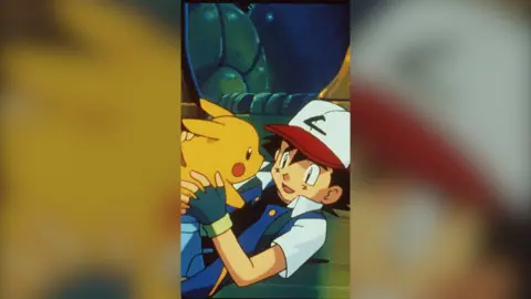 Cartoon image: Ash Ketchum holds Pikachu 