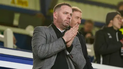 Portsmouth sporting director Richard Hughes in stand at Fratton park, with hands pressed together looking forward