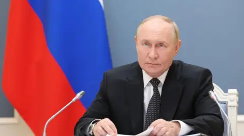 Russian President Vladimir Putin sitting in front of a Russian flag