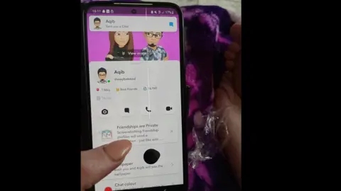 A woman's hand holding a smartphone with the Snapchat app on screen. 