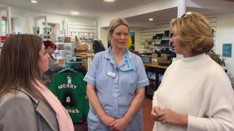 BBC/Nathan Turvey Nikki Smith (centre) who has blonde hair and is wearing a blue uniform meeting Louise Ryan (left) who has brown hair and is wearing a grey jacket and pink scarf and Clare Burton (right) who has blonde hair and is wearing a cream jumper. 
