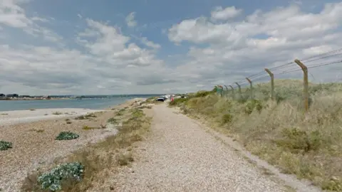 Shingle path and beach with expanse of water to the left.