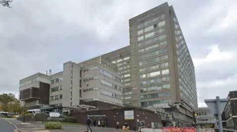 Google Maps The multi-storey concrete hospital building in Sheffield. Several people can be seen waiting at a bus stop outside the hospital.