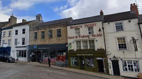 A picture of a row of shops on a cobbled street