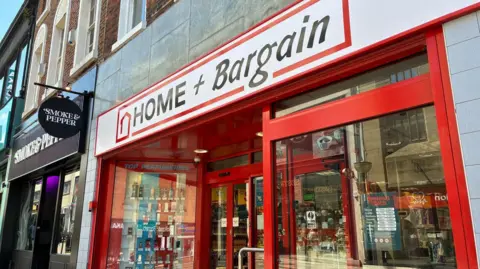 A red and white shop front with black writing which says Home and Bargain