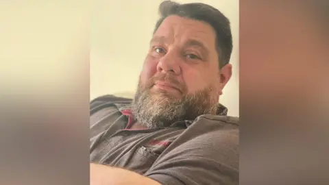 Sussex Police A man with a grey beard. He has quiffed brown hair. 