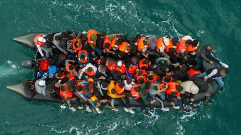 Reuters An aerial view of an inflatable dinghy overcrowded with migrants, motoring through the sea.