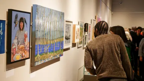 Worthing Theatres and Museum Visitors admiring a series of paintings at a museum.
