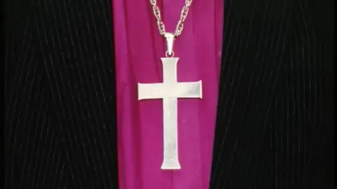 BBC Close-up of a cross necklace over gowns