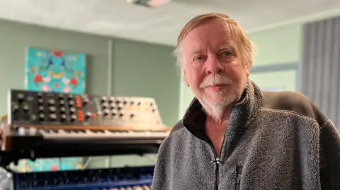 Jon Wright/BBC Rick Wakeman standing in front of some keyboards. 