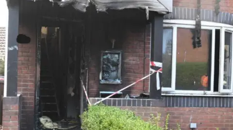 Greater Manchester Police Fire gutted semi-detached houses with scorcehd front door.