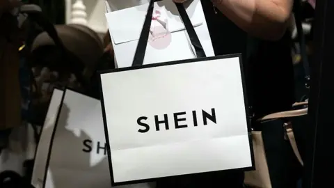 A picture of a shopper carrying a white Shein-branded shopping bag