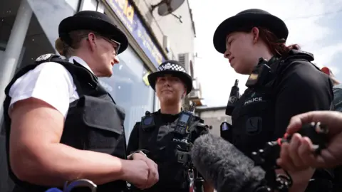 PA Media Serena Kennedy speaks to two uniformed police officers